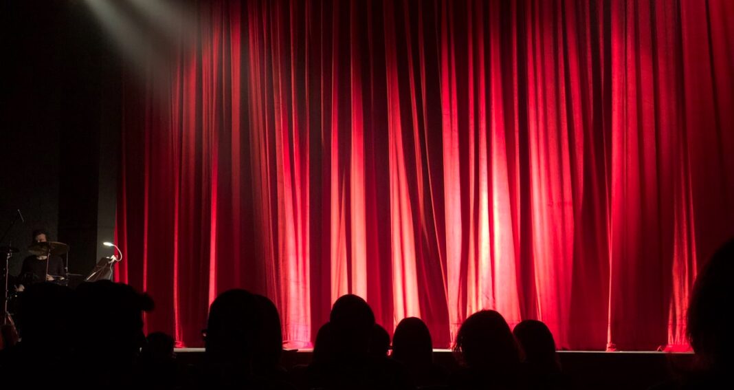 inside of theater with red curtain lit by spotlights