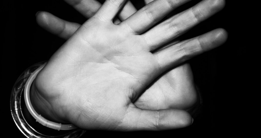 Two overlapping outstretched hands seen from the front indicating refusal to accept someone compelling an action..