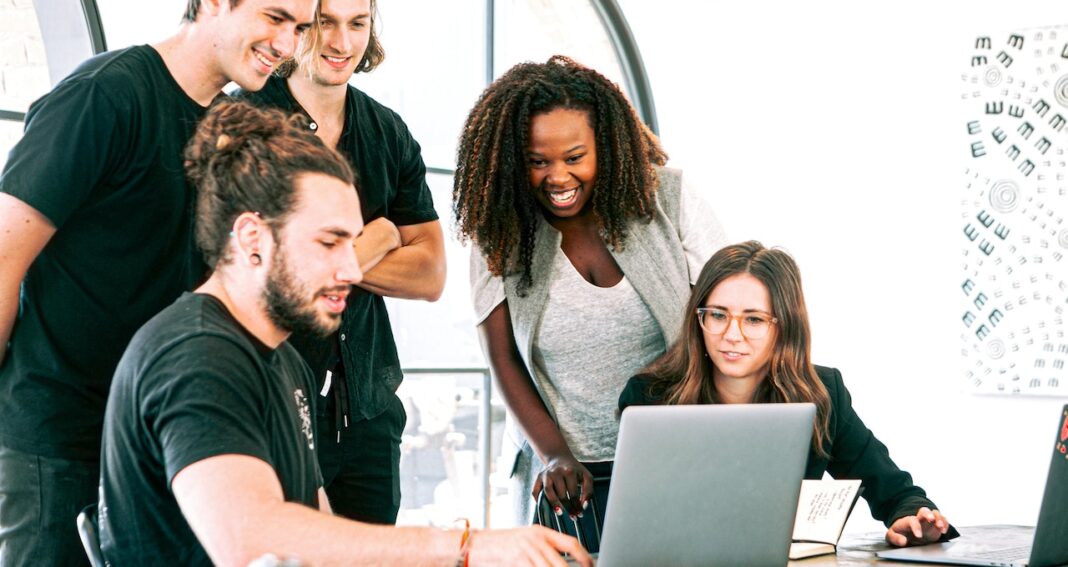 Workplace mental health can be seen in groups of people enjoying working together such as these people looking at something on a laptop.